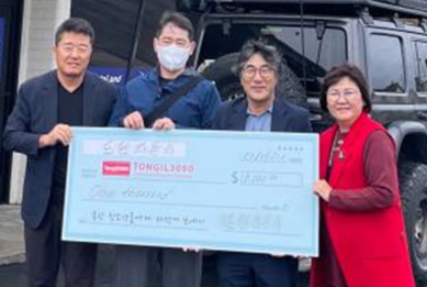 김동진(왼쪽에서 두 번째) 드림 자동차 대표가 최근 가든그로브의 사무실 앞에서 오득재(김 대표 오른쪽) 회장을 비롯한 통일3000재단 관계자에게 모형 수표를 건네고 있다. ［통일3000재단 제공］
