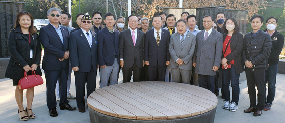 지난달 30일 기념비를 둘러본 민주평통 미주지역회의 간부들이 기념비를 배경으로 모여 기념 촬영을 하고 있다. ［건립위 제공］ 