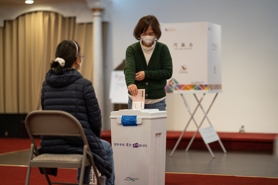 투표를 마친 한 유권자가 투표용지가 담긴 봉투를 수거함에 넣고 있는 모습. 