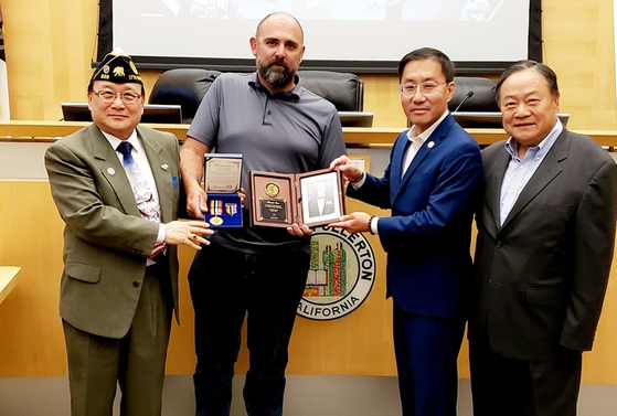 프레드 정(오른쪽에서 두 번째) 풀러턴 시장, 미 재향군인회 한인 829지부 토니 박(맨 왼쪽) 사령관이 워런 플로노이에게 수여하는 평화의 사도 메달과 추모패를 에릭 웬 전 풀러턴 공원국 커미셔너 위원장에게 전달하고 있다. 맨 오른쪽은 박동우 기념비 건립위원회 사무총장. [박동우 사무총장 제공]