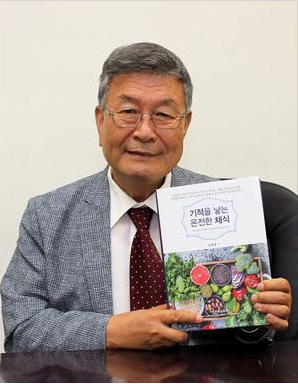 김평웅 원장이 자신의 저서 ‘기적을 낳는 온전한 채식’을 들어 보이고 있다. [가주 건강교육 파운데이션 제공]