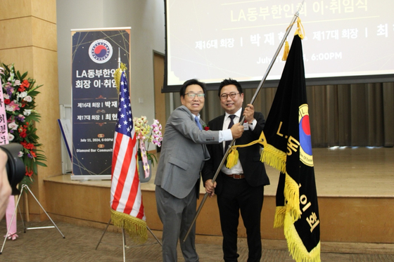 지난 11일 열린 제17대 LA동부한인회장 취임식에서 최현무 신임회장(오른쪽)이 전임 박재현 회장으로부터 한인회 깃발을 전달받고 있다. [LA동부한인회 제공]
