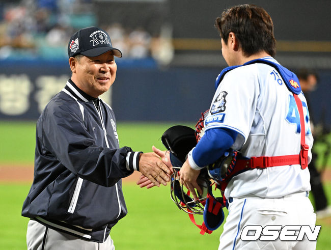 [OSEN=대구, 이대선 기자] 삼성 라이온즈가 25일 대구삼성라이온즈파크(이하 라팍)에서 열린 2024 신한은행 SOL 뱅크 한국시리즈 3차전에서 KIA 타이거즈를 4-2로 제압했다.이성규 김영웅 김헌곤 박병호가 차례로 솔로포를 터트렸다. 팀 한국시리즈 한 경기 최다 홈런이었다.선발 데니 레예스가 7이닝 1실점 눈부신 투구로 승리를 이끌었다. 2연패 후1승을 올리며 반격의 실마리를 잡았다.경기에 앞서 이만수 전 감독이 시포를 마치고 강민호와 인사르 하고 있다.  2024.10.25 / sunday@osen.co.kr