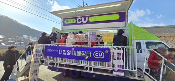 지난해 12월 26일 전북 진안군 진안읍 평촌마을을 찾은 '내 집 앞 이동장터(트럭)'에서 주민들이 식료품 등을 사려고 트럭에 설치된 계단을 오르고 있다. 진안=김준희 기자