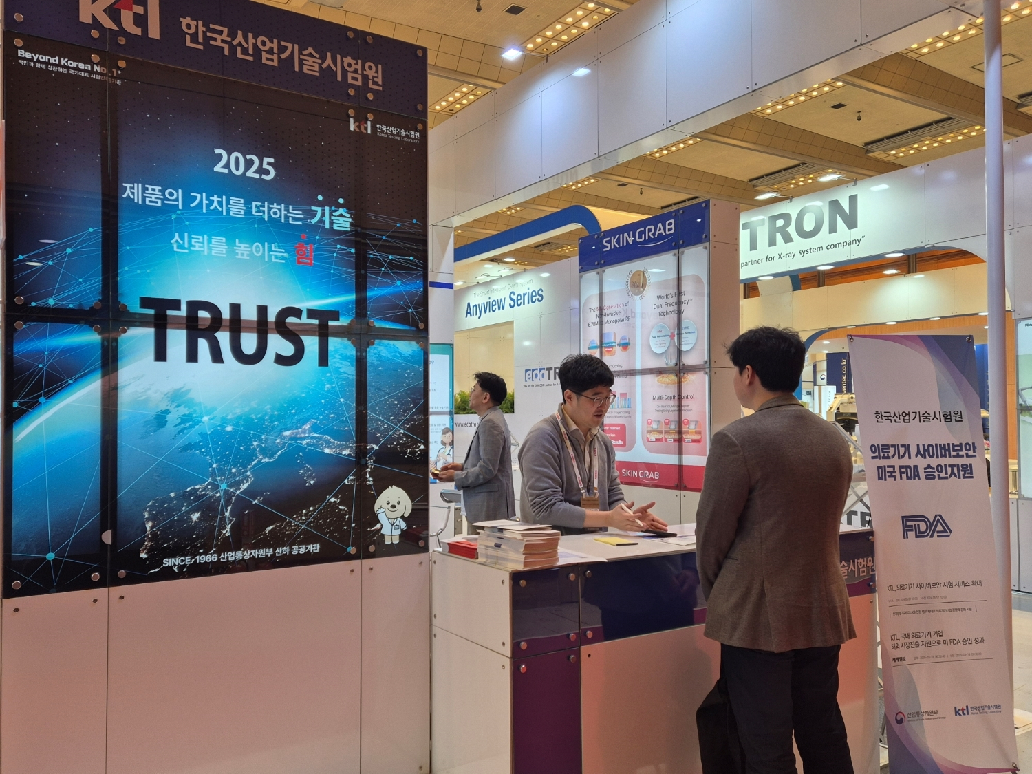 KTL 직원이 KIMES 2025 전시회에서 방문객에게 지원 사업에 대해 설명하고 있다.