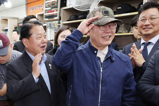 더불어민주당 이재명 대선 후보가 2일 강원도 화천군 한 군장점에서 김병주 최고위원이 사준 병장 계급장이 달린 육군 모자를 써보고 있다. 연합뉴스