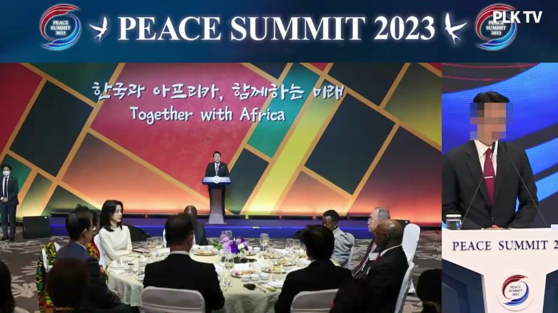 지난해 5월 서울 잠실 롯데호텔월드에서 열린 피스 서밋(PEACE SUMMIT) 2023 개회식에서 당시 통일교 세계본부장 윤모씨가 자료 사진으로 2022년 11월 아프리카 대사단 초청 만찬에서 연설하는 윤석열 전 대통령과 자리에 앉은 김건희 여사 사진을 띄워놓고 개회사를 하고 있다. 사진 독자 제공