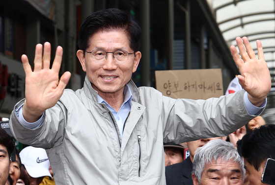 김문수 국민의힘 대통령 후보가 6일 경북 포항시 죽도시장에서 시민들을 향해 인사하고 있다. 뒷편에는 한 지지자가 '양보 하지 마세요'라고 적힌 종이를 들어보이고 있다. 뉴스1
