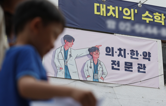 지난해 5월 서울 강남구 대치동 의대 입시학원 현수막 아래로 유치원생이 걸어가고 있다. 뉴스1