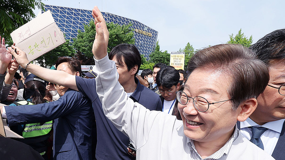 이재명 더불어민주당 대선후보가 ‘골목골목 경청투어’ 사흘째인 7일 전북 전주 풍남문 앞 광장에서 ‘공판 연기 환영’ 손팻말을 든 지지자들을 향해 손을 들어 인사하고 있다. 이날 서울고법은 이 후보의 공직선거법 위반 혐의 사건 파기환송심 첫 공판을 6월 18일로 연기했다. [연합뉴스]