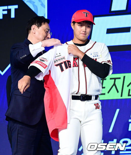 [OSEN=지형준 기자] 11일 오후서울 잠실 롯데호텔 월드에서 2025 KBO 신인 드래프트가 열렸다.2025 KBO신인 드래프트는 전면 드래프트 방식으로 진행된다. 지명은 1라운드부터 11라운드까지 이뤄지며, 2023년도 구단 순위의 역순인 키움-한화-삼성-롯데-KIA-두산-NC-SSG-KT-LG 순서로 실시된다.덕수고 김태형이 KIA에 1라운드 지명되며 심재학 단장이 유니폼을 전달하고 있다. 2024.09.11 / jpnews@osen.co.kr