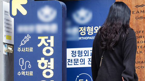 한 시민이 정형외과의원의 홍보물을 지나고 있다. 뉴스1