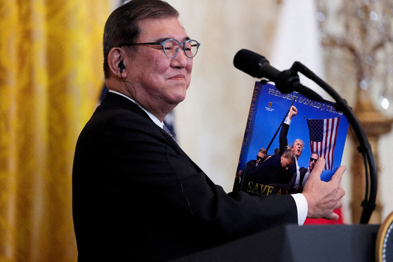 이시바 시게루 일본 총리가 2025년 2월 7일 미국 워싱턴 백악관 이스트룸에서 공동기자회견을 열고 도널드 트럼프 미국 대통령의 선물을 보여주고 있다. 로이터=연합뉴스