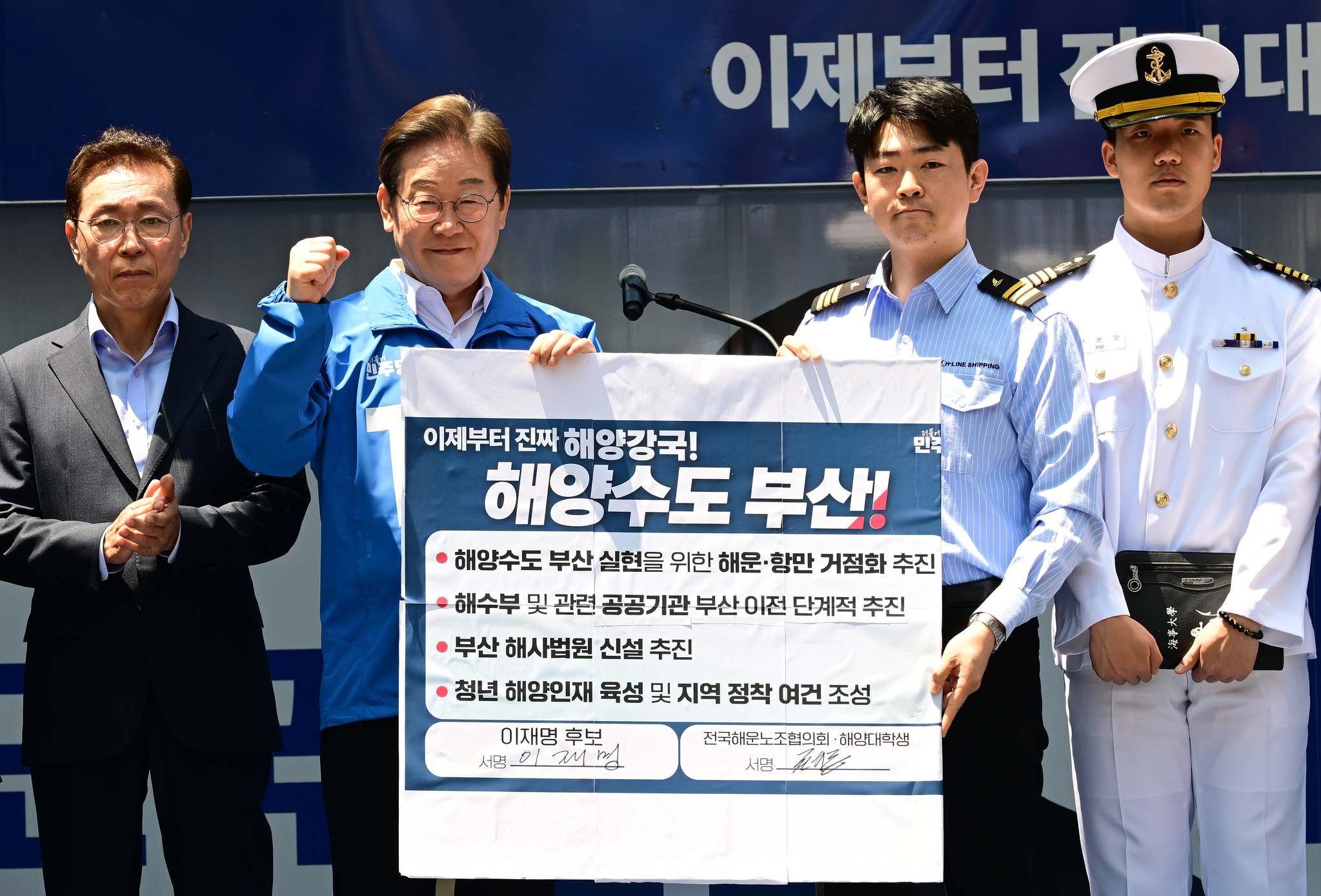 이재명 더불어민주당 대통령 후보가 14일 부산 부산진구 서면에서 권기흥 에이치라인해운해상직원노조 위원장과 해양수도 부산 협약서에 서명한 뒤 들어보이고 있다. 김성룡 기자