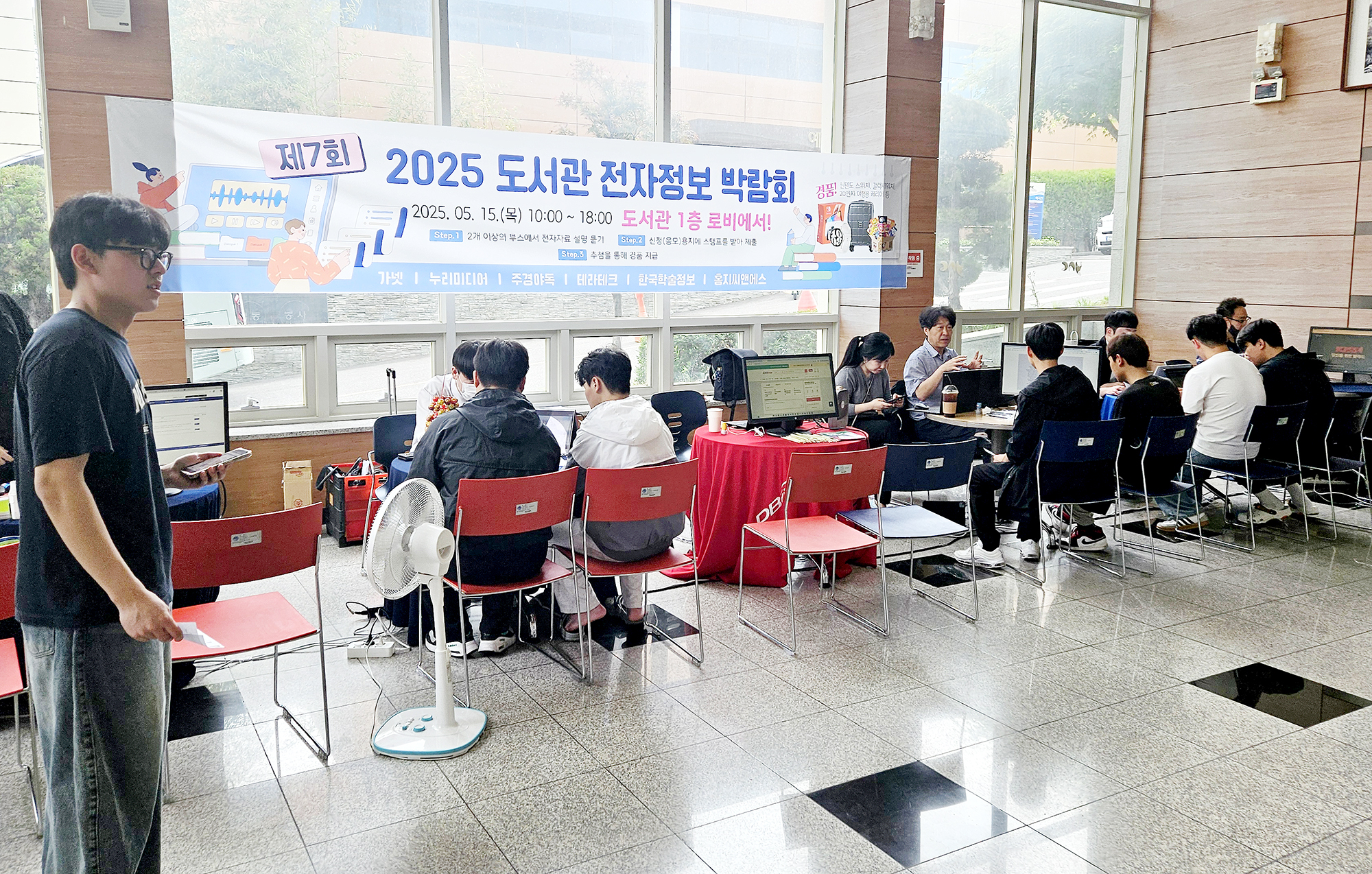 학생들이 행사 부스에서 전자정보에 관한 설명을 듣고 있다