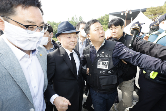 45주년 5·18 민주화운동 기념식이 열린 18일 오전 광주 북구 운정동 국립 5·18 민주묘지 민주의문 앞에서 시민들의 항의를 받은 안창호 국가인권위원장이 경호를 받으며 돌아가고 있다. 공동취재