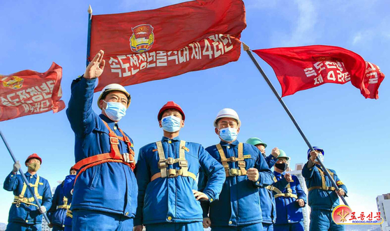 화성지구 1만 세대 살림집 건설에 참가한 '속도전청년돌격대 제4여단의 지휘관, 대원들이 속도전 슬로건이 적힌 깃발을 들고 있는 모습. 노동신문, 뉴스1
