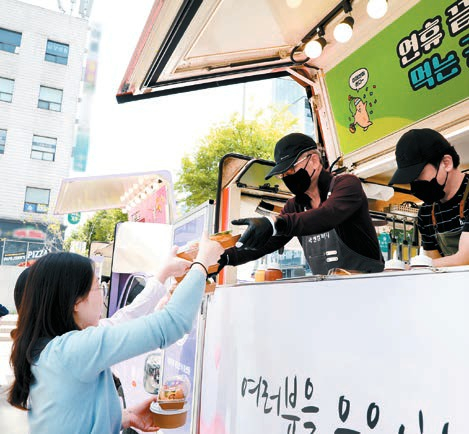 임직원들이 가정의 달을 맞아 점심시간 진행된 사내 교류 푸드트럭 행사에서 제공된 음식을 받고 있다. [사진 미래엔]