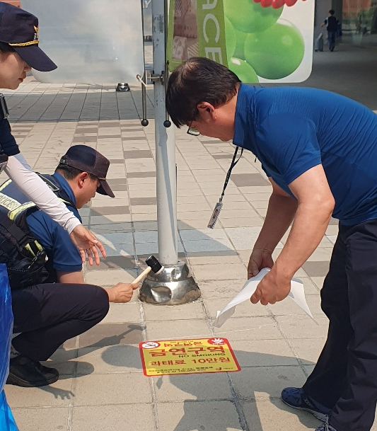 서울 중구청 직원과 경찰들이 서울역광장에 금연구역 알림 스티커를 노면에 붙이고 있다. 사진 서울 중구