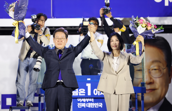 제21대 대통령 당선이 확실시되는 더불어민주당 이재명 대선 후보와 부인 김혜경 여사가 4일 서울 여의도 국회 인근에서 당 주최로 열린 국민개표방송 행사에 참석해 박찬대상임총괄선대위원장과 정은경 총괄선대위원장단으로부터 꽃다발을 받은 뒤 시민들을 향해 두 팔을 들어 인사하고 있다. 공동취재