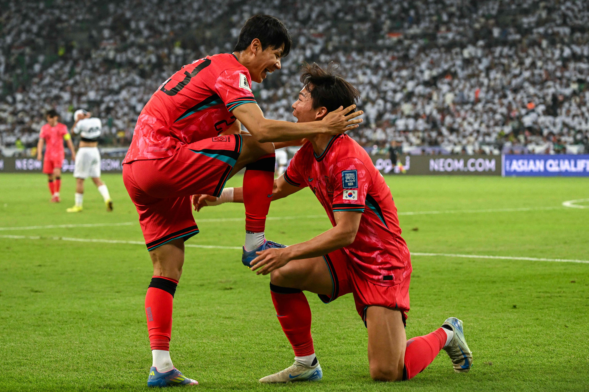 축구대표팀 오현규(오른쪽)가 지난 6일 이라크와의 북중미월드컵 아시아 3차예선 이라크전에서 골을 어시스트해준 전진우의 축구화를 닦아주는 세리머니를 펼치고 있다. [AFP=연합뉴스]