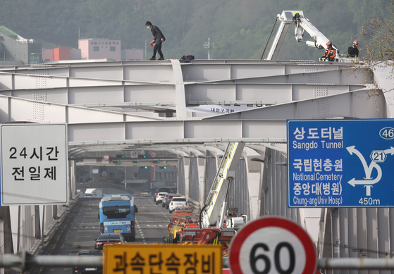 지난해 4월 17일 한 남성이 서울 용산구 한강대교 아치 위에 올라가 투신을 시도하겠다며 소방대원과 대치하는 모습. 당시 이 소동으로 인근 교통이 통제돼 출근길 차량 정체가 극심했다. 연합뉴스