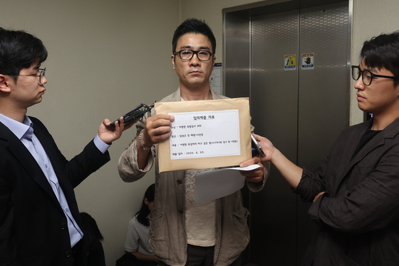 전직 해병 이관형씨가 20일 서울 서초구 이명현 특별검사의 사무실을 찾아 입장 등이 담긴 문서를 제출하려다 불발되자 취재진에 문서를 들어보이고 있다. 연합뉴스