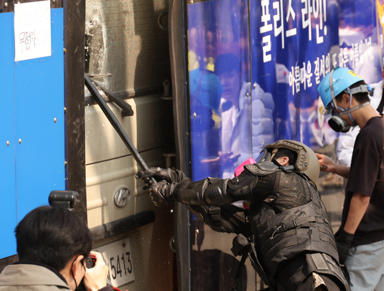 지난 4월 4일 서울 종로구 헌법재판소 인근에서 윤석열 대통령 지지 집회 참가자 중 한 명이 헌재의 윤 대통령 파면 결정에 경찰이 세운 가벽 사이로 보이는 차량을 부수고 있다. 연합뉴스