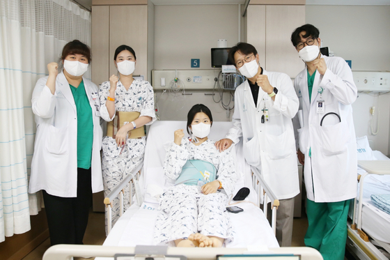 다낭성 신증후군으로 만성 신부전을 앓던 이가영 씨(가운데)가 로봇 신장이식 후 순조롭게 회복하며 20일(금) 의료진과 기념사진을 찍고 있다. 왼쪽에서 두 번째가 공여자인 언니 이 모 씨, 네 번째가 수술을 집도한 서울아산병원 신·췌장이식외과 신성 교수.