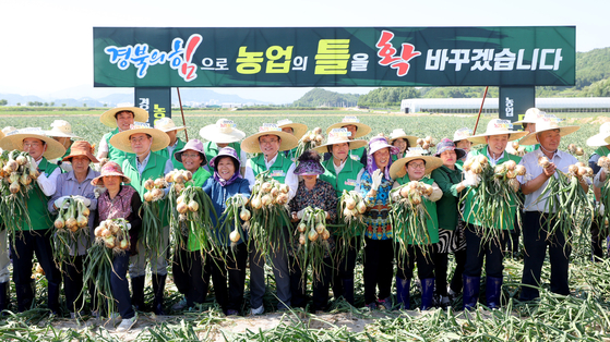 지난해 5월 23일 경북 문경시 영순면 공동영농단지에서 ‘경북 농업대전환 공동영농 성과 보고회’가 열린 가운데 참석자들이 농민들과 함께 수확한 양파를 들고 기념촬영하고 있다. 사진 경북도