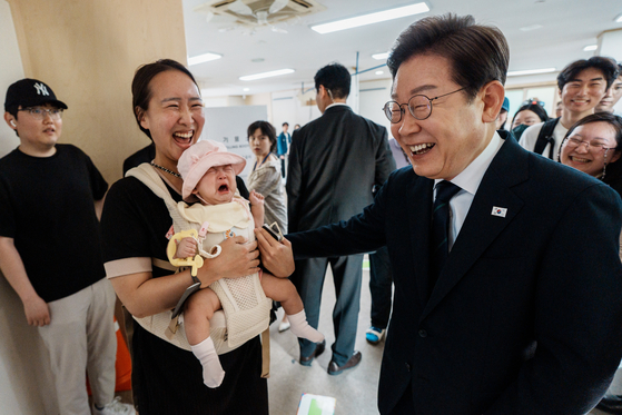 지난 5월 이재명 당시 대통령 후보가 서울 서대문구 신촌동주민센터에서 아이를 안은 주민과 인사하는 모습. [뉴스1]