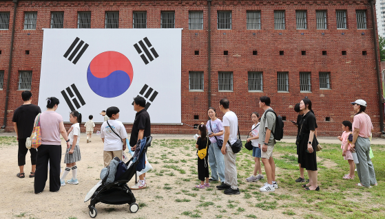 지난해 8월 15일 제79주년 광복절을 맞아 서울 서대문형무소역사관의 대형 태극기 앞에서 시민들이 기념 촬영을 하고 있다. [뉴스1]
