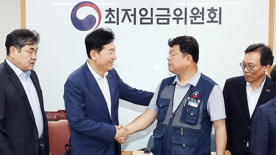 최저임금위원회 사용자위원 운영위원인 류기정 한국경영자총협회 전무(왼쪽)와 근로자위원 운영위원인 류기섭 한국노총 사무총장이 10일 정부세종청사에서 열린 제12차 전원회의에서 내년 최저임금을 시간당 1만320원으로 17년 만에 합의로 결정한 뒤 악수하고 있다. 왼쪽은 이인재 위원장, 오른쪽은 이명로 중소기업중앙회 인력정책본부장. 연합뉴스