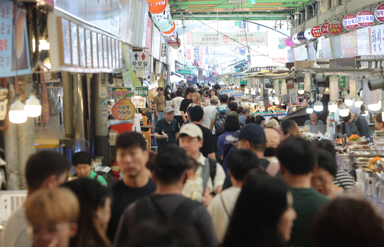 서울의 한 전통시장을 찾은 시민들이 점포를 둘러보고 있다.   경기 진작을 위한 이재명 정부의 첫 민생회복 소비쿠폰 신청과 지급이 이달 21일부터 시작한다. [연합뉴스]
