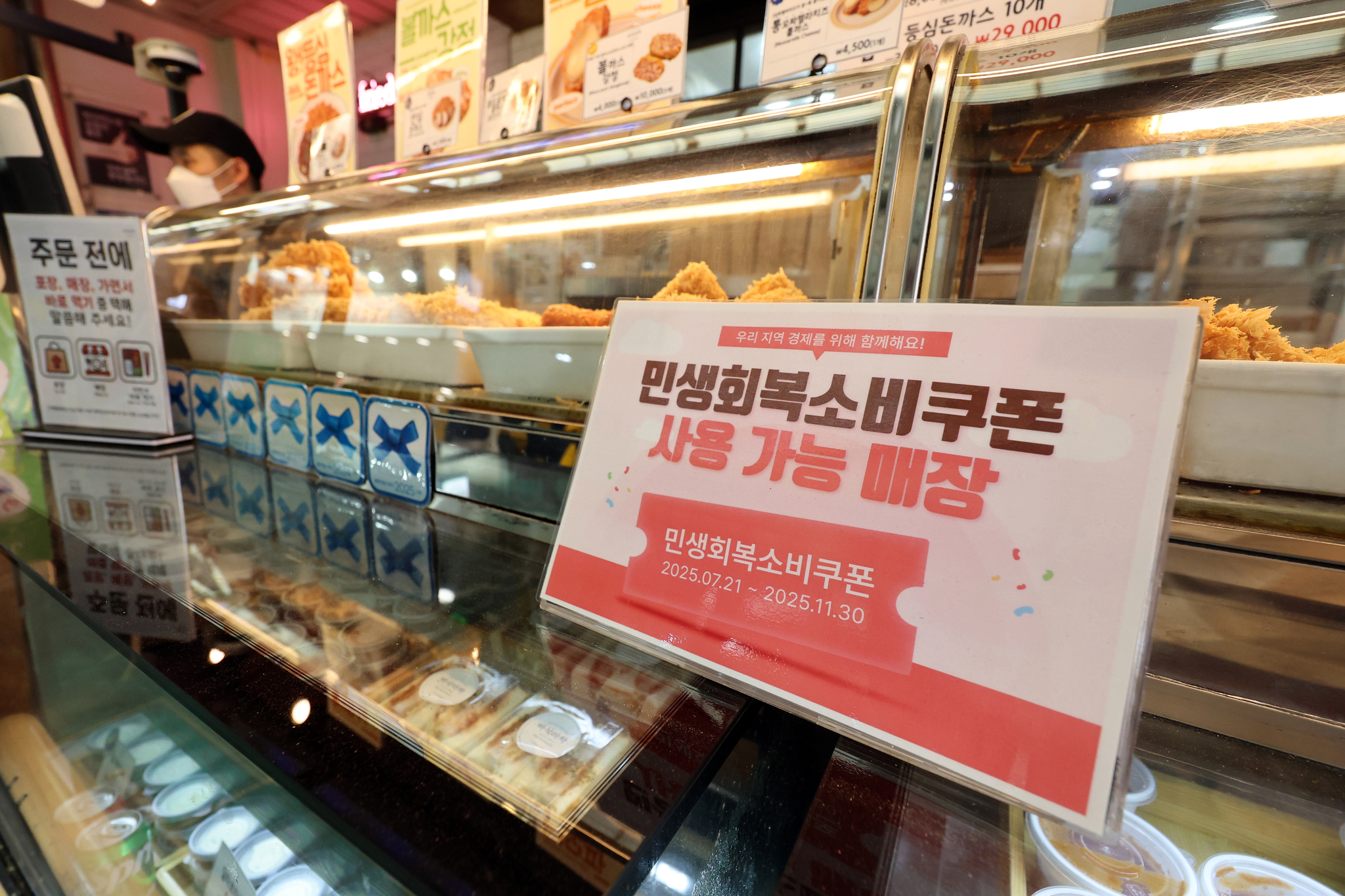 민생회복 소비쿠폰 1차 신청 첫 날인 21일 서울의 한 돈가스 전문점에 쿠폰 사용 관련 안내문이 붙어있다. 뉴스1