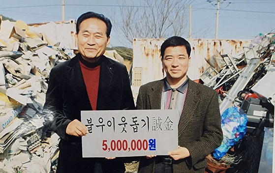 2005년 태안신협 문기석 이사장이 고철과 폐지를 쌓아 놓은 공터에서 당시 진태구 태안군수(왼쪽)에게 불우이웃돕기 성금을 전달하고 있다. [사진 문기석 이사장]