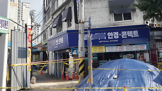 24일 오후, 지반 침하 현장 바로 옆 상가 건물이 기울어져 출입이 통제되고 있다. 상가 건물 앞으로는 무너진 지반을 임시로 메우고 난 토사 등이 쌓여 있다. 전율 기자