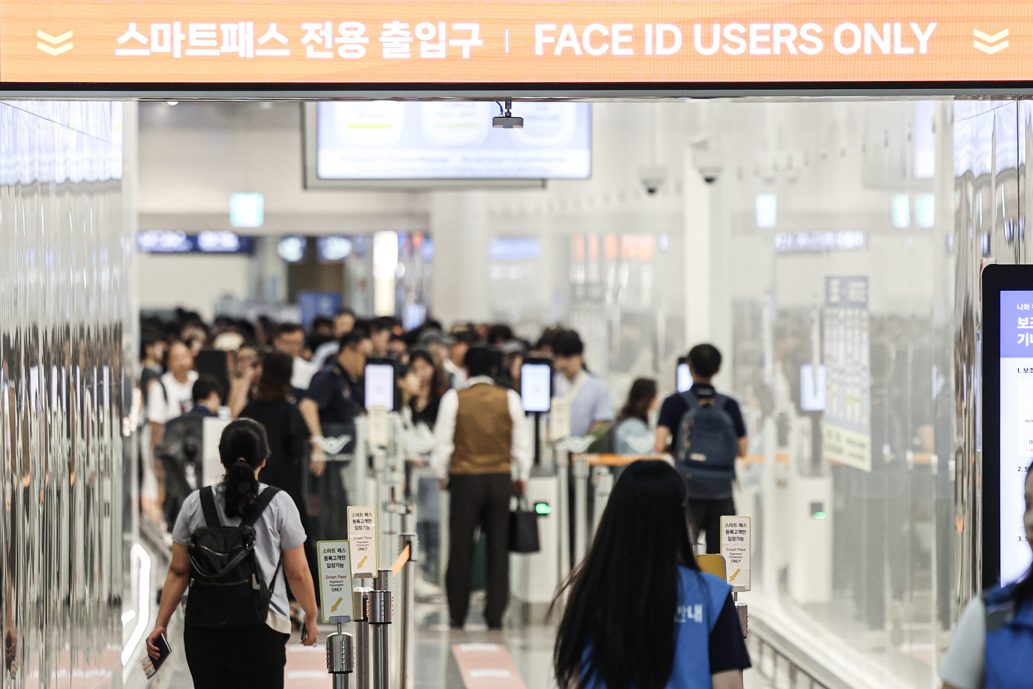 한산한 T1 스마트패스 전용 출입구 너머로 붐비는 일반여객 출입구가 보인다.