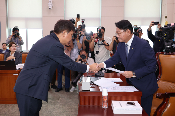 최휘영 문화체육관광부 장관 후보자가 29일 서울 여의도 국회 문화체육관광위원회에서 열린 인사청문회에서 선서문을 더불어민주당 소속 김교흥 위원장에게 전달한 뒤 악수하고 있다. 연합뉴스
