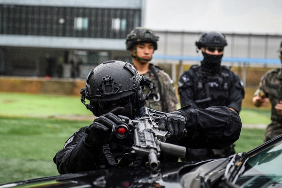 차량 근접전술 사격(VCQB) 훈련에서 차량에 몸을 숨겨 사격하고 있는 공군 장병. 육군 장병이 뒤에서 이를 지켜보고 있다. 공군 17전비