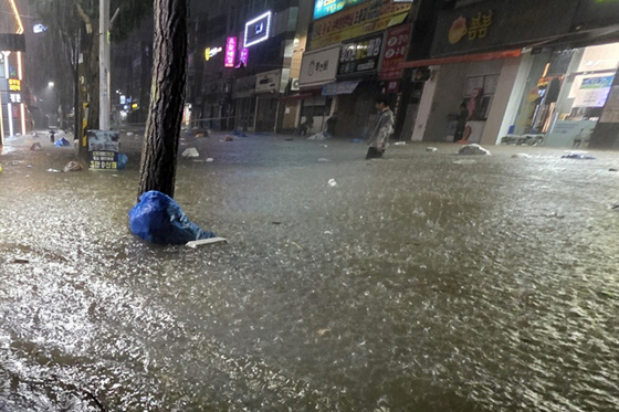 무안군을 중심으로 광주·전남 곳곳에 극한호우가 쏟아진 3일 오후 광주 북구 운암동 도심에서 한 시민이 침수된 거리를 이동하고 있다. 연합뉴스