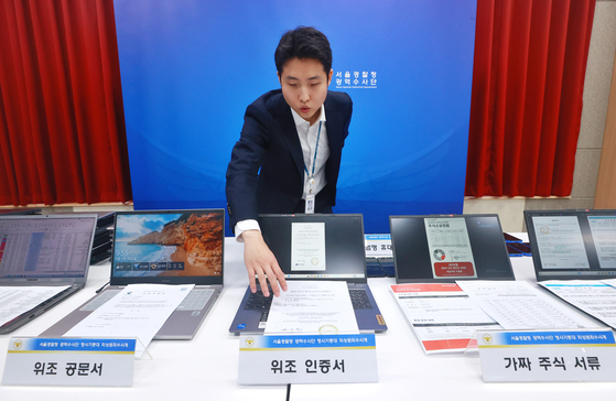 5일 서울 마포구 서울경찰청 광역수사단에서 남철안 서울경찰청 광역수사단 형사기동대 피싱범죄수사계 관계자가 '주식 거래 빙자' 신종 피싱조직 검거 관련 브리핑에 앞서 가짜 주식 서류, 위조 인증서 등을 나열하고 있다. 연합뉴스