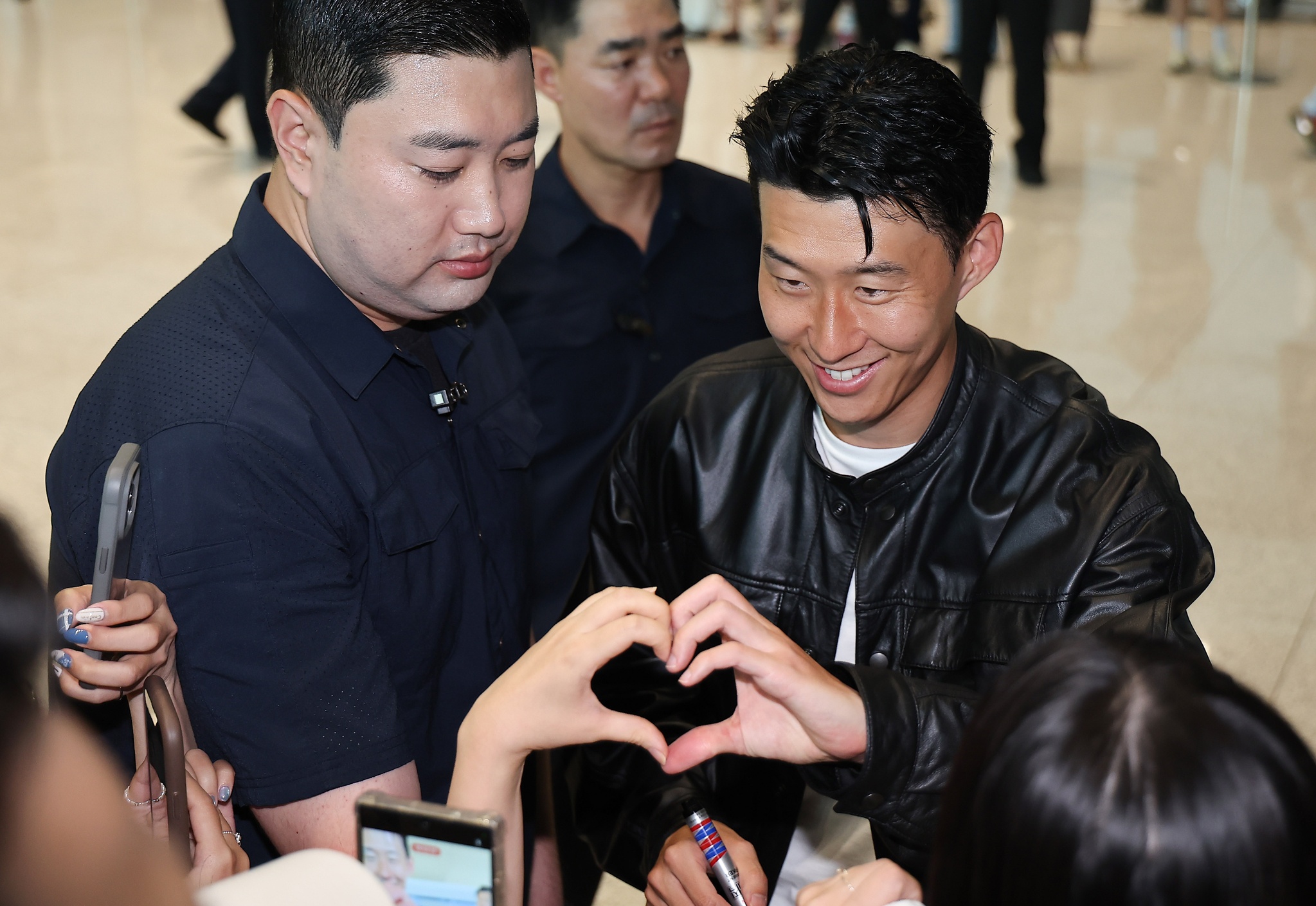 토트넘과의 결별 소식을 전한 손흥민이 5일 인천 영종도 인천국제공항 2터미널 출국장으로 향하며 팬과 손하트하고 있다. [연합뉴스]