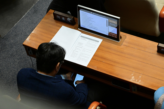 ‘주식 차명거래 의혹’이 확산하자 5일 밤 더불어민주당을 탈당한 이춘석 의원이 지난 4일 국회 본회의장에서 휴대전화로 타인 명의 주식 계좌를 확인하고 있는 모습. [사진 더팩트]