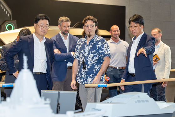 6일 HD현대 글로벌R_D센터를 방문한 팔머 럭키(Palmer Luckey) 안두릴 공동설립자(앞줄 가운데)가 주원호 HD현대 특수선사업대표(앞줄 왼쪽)으로 부터 HD현대가 개발 중인 무인수상정에 대한 설명을 듣고 있다. 사진 HD현대
