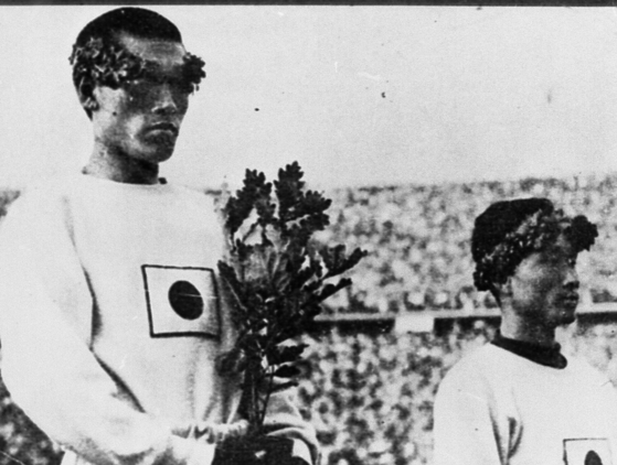 1936년 베를린 올림픽 마라톤 우승 후 시상대에 오른 손기정 선수. 일장기가 붙은 가슴까지 월계수 묘목을 당겨 안았다. [중앙포토]