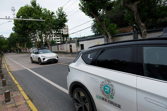 지난해 7월 19일 중국 IT기업 바이두의 로보택시 서비스인 아폴로 고의 자율주행 차량(로보택시)이 중국 후베이성 우한의 도로변에 주차된 다른 아폴로 고 로보택시를 지나가고 있다. 로이터=연합뉴스