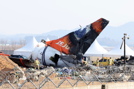 제주항공 여객기 참사 16일째인 지난 1월 13일 무안국제공항 사고 현장에서 소방 대원들이 기체에 덮인 방수포를 걷어내고 있다. 연합뉴스
