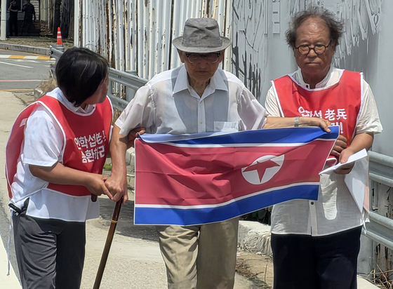 20일 오전 경기도 파주시 통일대교 남단에서 북한 송환을 요구한 비전향장기수 안학섭 씨(가운데)가 인공기를 펼쳐 들고 있다. 연합뉴스