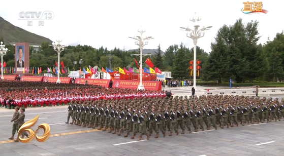 21일 중국 티베트 라싸에서 열린 자치구 성립 60주년 경축대회에서 여성 민병대오가 행군하고 있다. 포탈라궁 광장에 세워진 시진핑 주석의 대형 초상화가 보인다. CC-TV 캡처